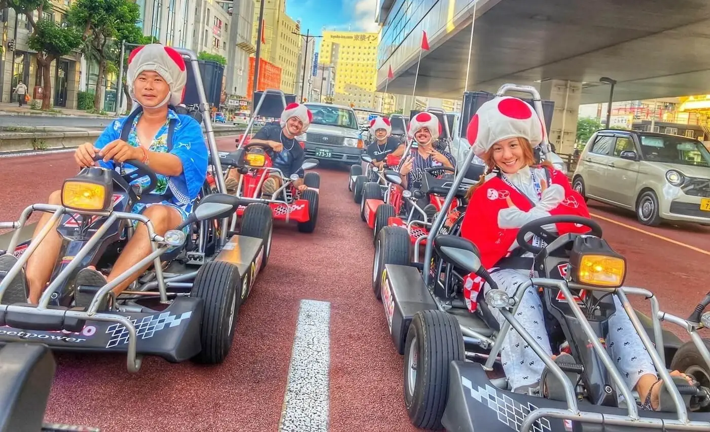 A kart convoy moving up Kokusai Dori past shopfronts and parked cars