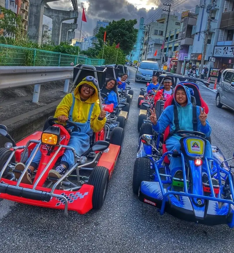 A convoy of red and blue go karts on a main road through Naha