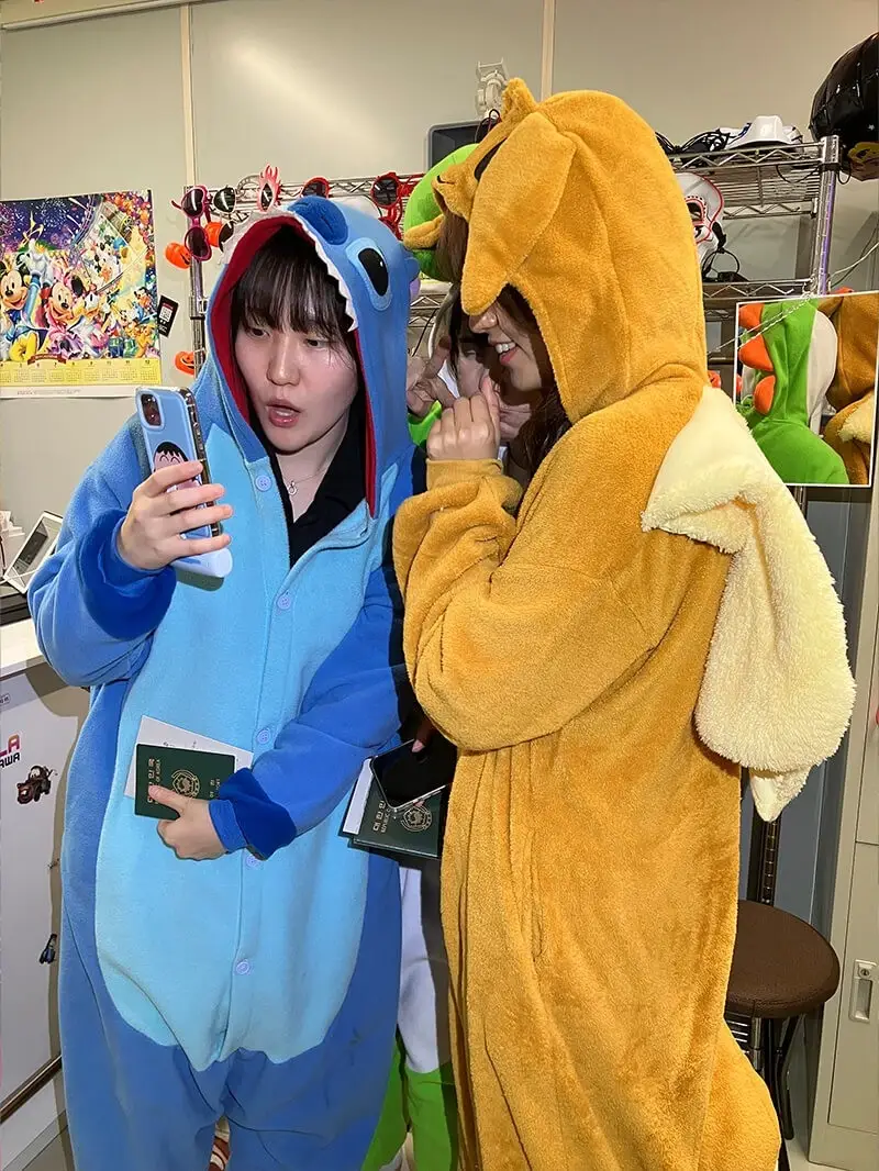 Two riders in Stitch and Charmander onesies taking a selfie inside the Gorilla Kart shop