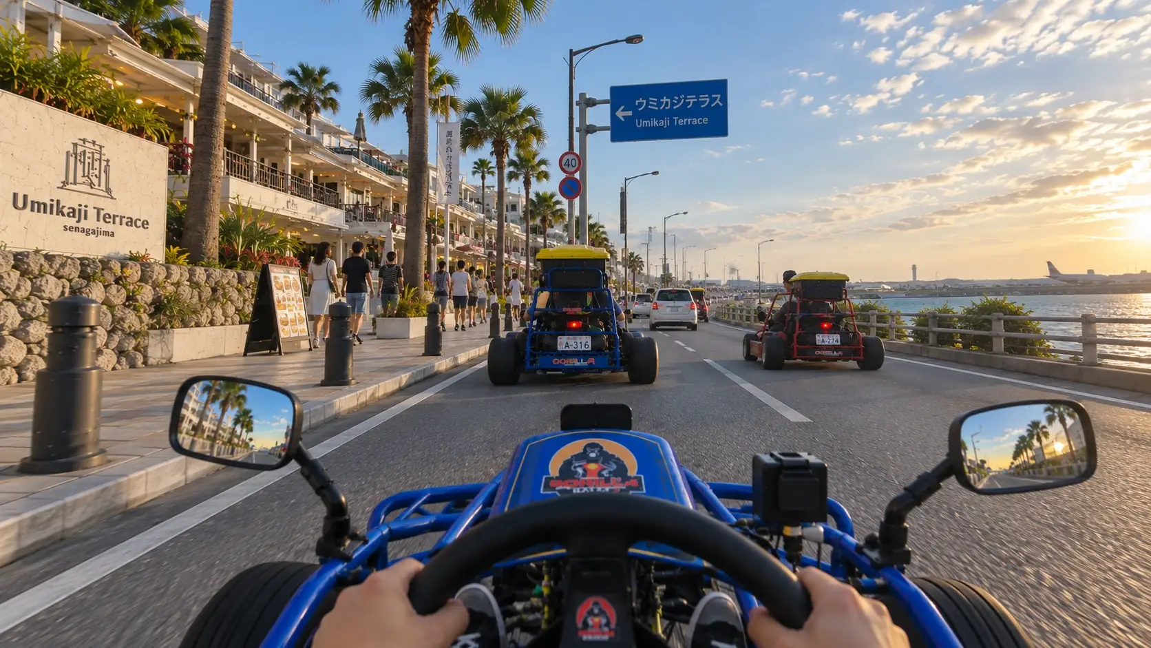 The view from behind the wheel of a Gorilla Kart go-kart, driving along the Umikaji Terrace waterfront on Senaga Island at sunset, with two more karts ahead