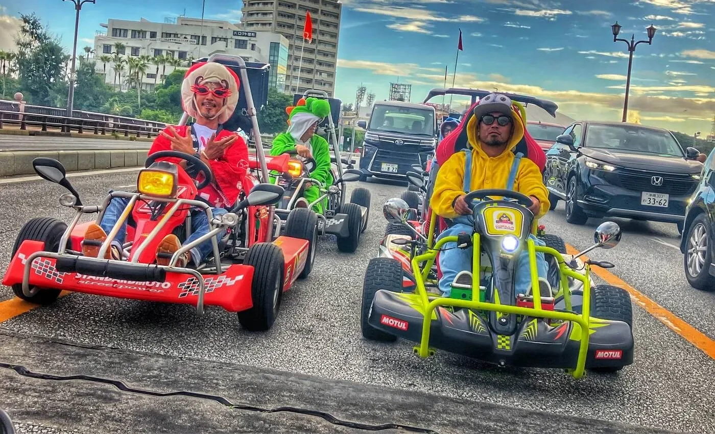 Two karts side by side on a Naha street at dusk